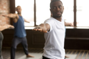 young sporty black man in warrior two exercise